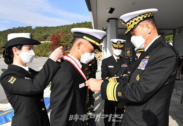 해군은 “27일 오후 2시 해군사관학교 연병장에서 제129기 해군․해병대 학사사관 임관식을 거행했다”고 밝혔다.사진은 김명수 해군사관학교장이 국방부장관상을 수상한 오도형 해군소위에게 상장을 수여하고 메달을 걸어주고 있다.(사진_해군)