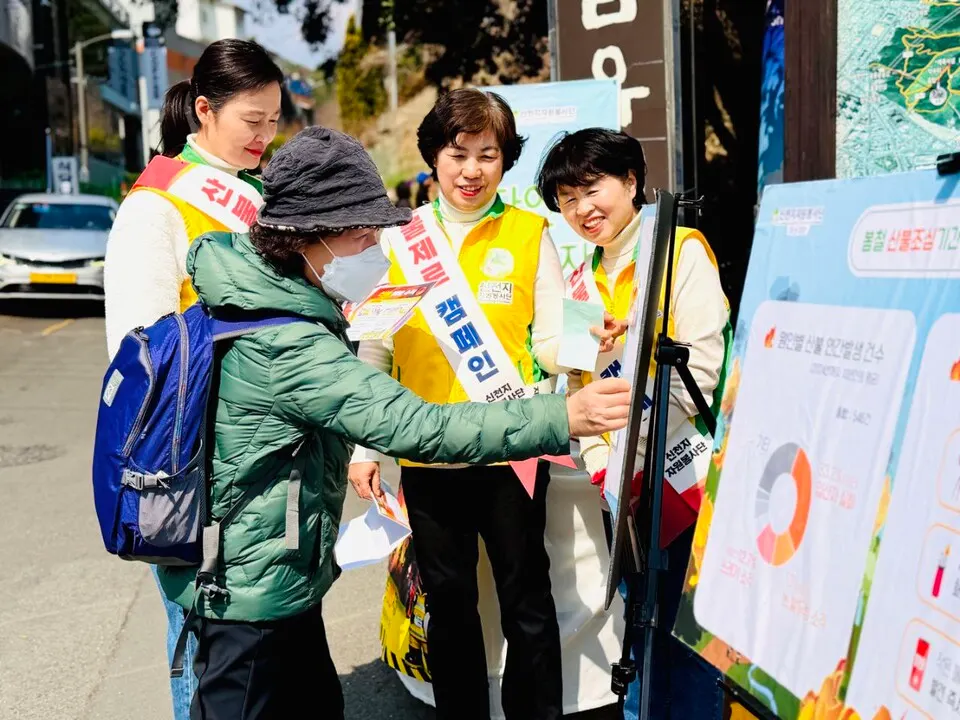 지난 17일 봉암수원지에서 신천지자원봉사단 마산지부가 산불 예방 캠페인을 진행하는 가운데 시민이 홍보물에 스티커를 붙이고 있다.(사진_신천지자원봉사단 마산지부)