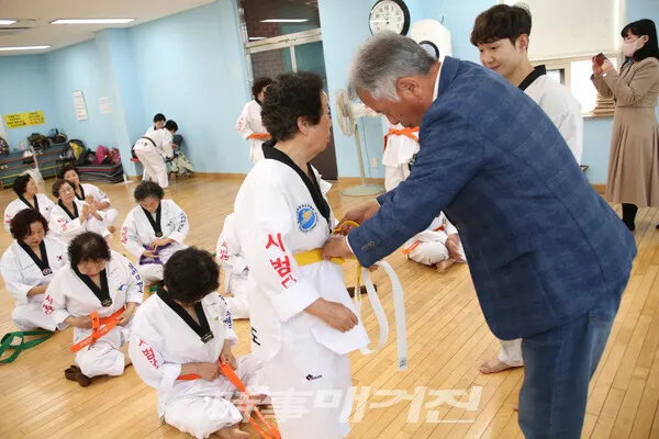 심사를 마치고 최고령 박영임(82세) 어르신께 띠를 매고 있는 이희승 광주광역시 태권도협회 부회장.(사진_정연수기자)