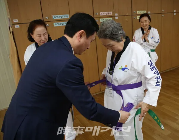 심사자 중 가장 연세가 많으신 임용여(84세) 어르신께 띠를 매드리고 있는 임동대 강사 (사진_정연수기자)