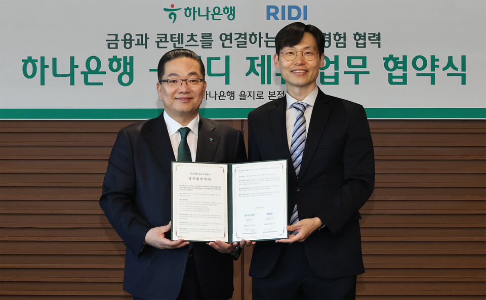 지난 10일 이호성 하나은행장(왼쪽)과 배기식 리디 대표이사가 서울 을지로 하나은행 본점에서 금융·콘텐츠 결합을 통한 새로운 고객 경험 제공 업무협약을 체결한 뒤 협약서를 들고 기념촬영을 하고 있다.(사진_하나은행)