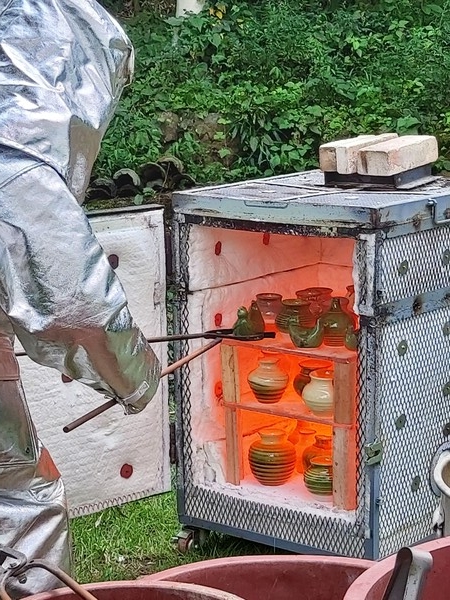 박현수 교수가 라쿠가마에서 1050℃로 가열된 도자기를 방화복을 입고 꺼내고 있다(사진-이용찬).