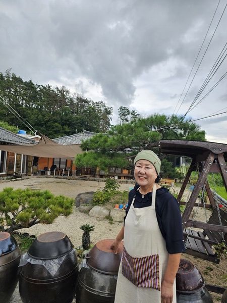 기장발효 이순옥 대표가 전통 장독대가 놓인 양조장 앞에서 기장 특산물을 활용한 전통주 제조 현장을 소개하고 있다.(사진_기장발효)