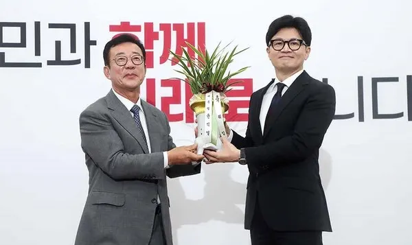 한동훈 국민의힘 신임 대표가 24일 오후 국회를 예방한 홍철호 대통령실 정무수석으로부터 윤석열 대통령의 축하 난을 받고 있다.(사진_국민의힘)