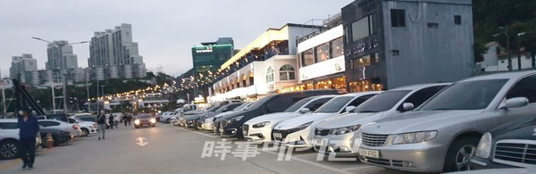 꽉 차 빈틈이 없는 주차장과 지나가는 사람들에게 여기저기 호객하는 상인들 (사진_ 조대웅 기자)