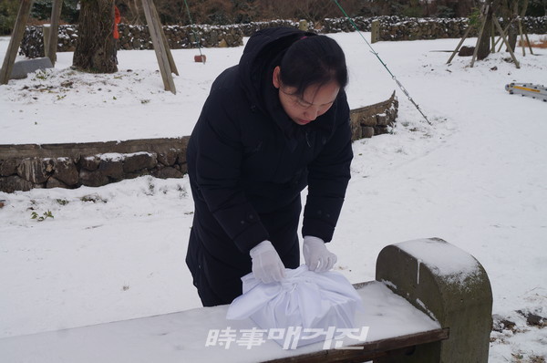위패를 정성들여 보자기로 싸고 있다.