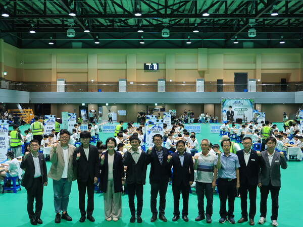 합천다목적체육관에서 열린 '2026 하찬석국수배 어린이바둑대회' 참석자들이 대국 중인 어린이들을 배경으로 기념촬영을 하고 있다.(사진_합천군)